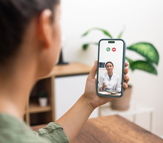 Person receiving medical consultation through a video call with a smiling doctor on a smartphone